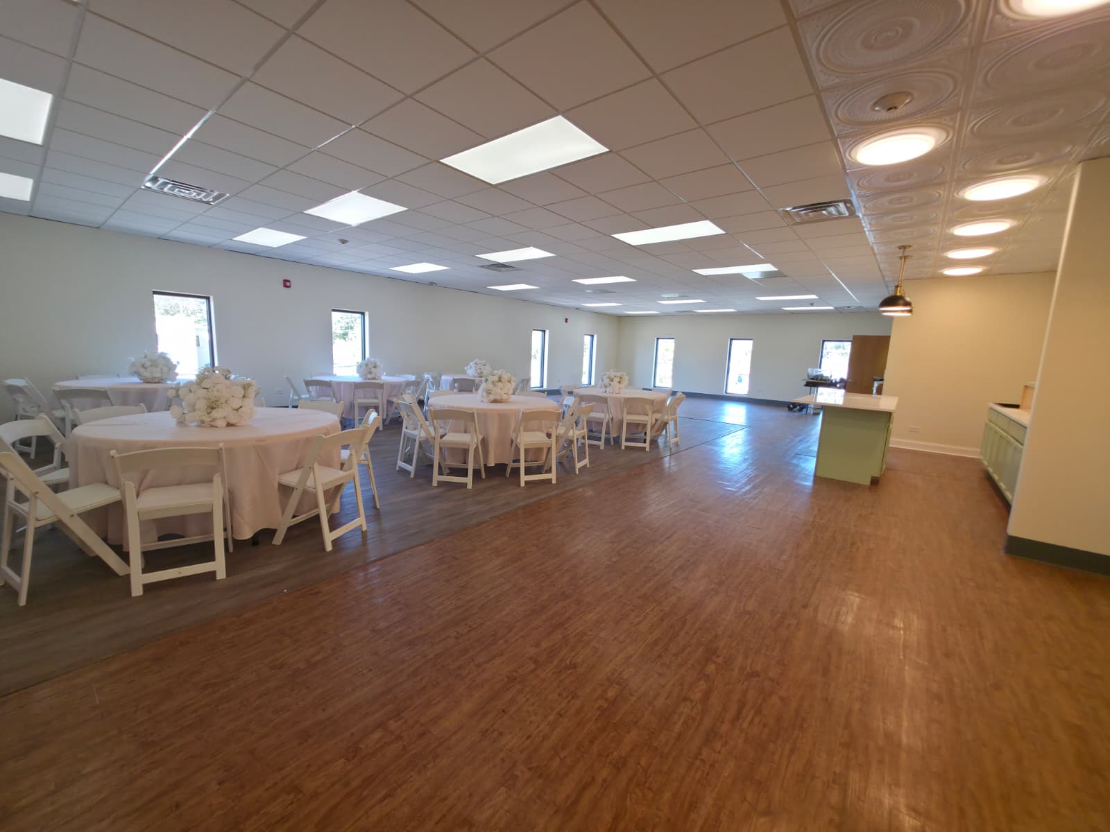 The Metro Room with round tables, white chairs, floral centerpieces and a green counter